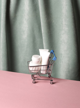 Shopping trolley with Cream tubes against the background of curtain. Aesthetic beauty still life. Minimalism.の写真素材