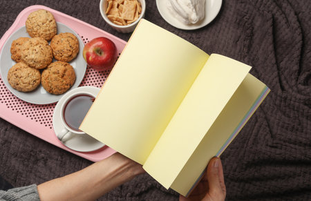 Hands holding blank notebook and breakfast in bedの写真素材