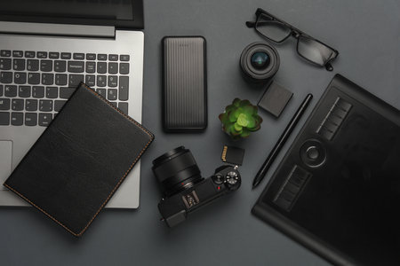 Laptop with camera and photography accessories on a black background. Top viewの写真素材