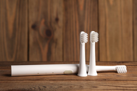 Modern ultrasonic cordless toothbrush with replaceable heads on wooden backgroundの写真素材