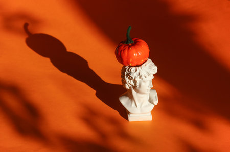 David bust and pumpkin with shadows on orange background. Halloween conceptの写真素材