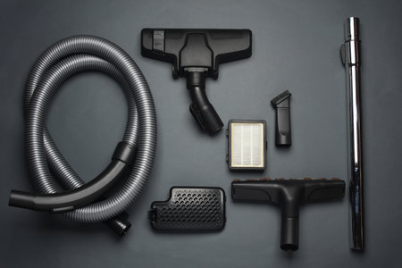 Components and attachments of a modern vacuum cleaner on dark background. Top view. Flat layの写真素材