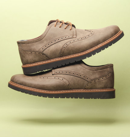 Leather brogue shoes floating on green background