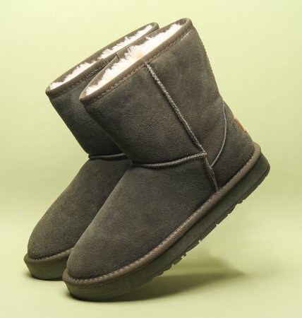 Pair of women's suede winter boots with fur on a green background