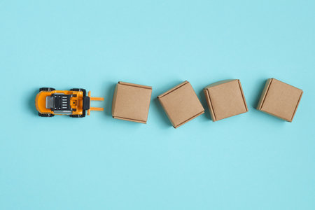Toy forklift with boxes on a blue background. Logistics, delivery