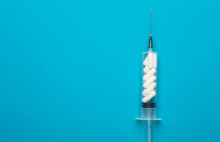 The syringe is filled with pills on a blue background. Healthcare and medicine conceptの写真素材
