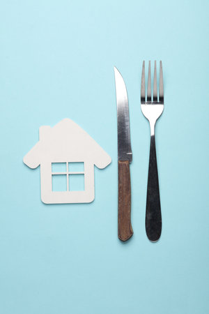 House model with fork and knife on blue background