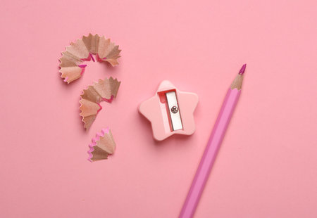 Sharpened pencil with shavings and sharpener on pink backgroundの写真素材