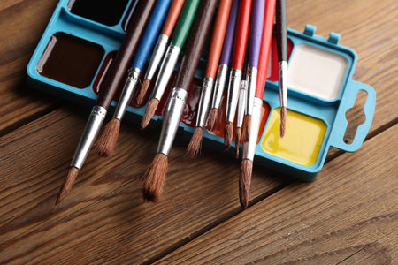 Watercolor paints with brushes on wooden backgroundの写真素材