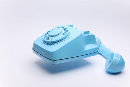 Blue retro rotary phone floating on white backgroundの写真素材