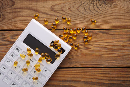 Fish oil capsules with calculator on a wooden table.の写真素材