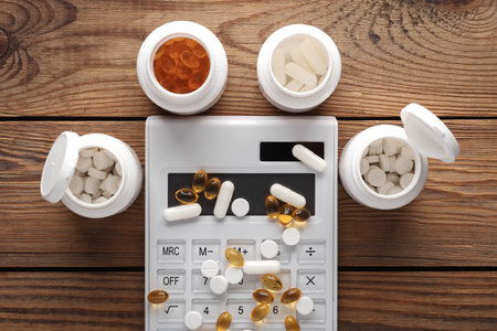 Different types of pills with a calculator on a wooden table. Medicine conceptの写真素材