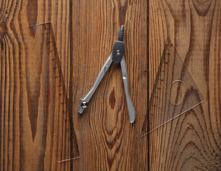 Compasses with rulers on a wooden tableの写真素材