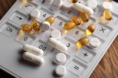 Different types of pills with a calculator on a wooden table. Medicine conceptの写真素材