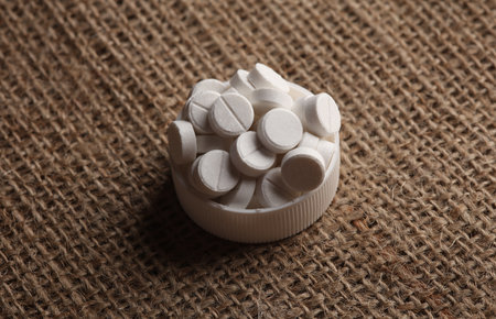 White Pills on burlap background close up