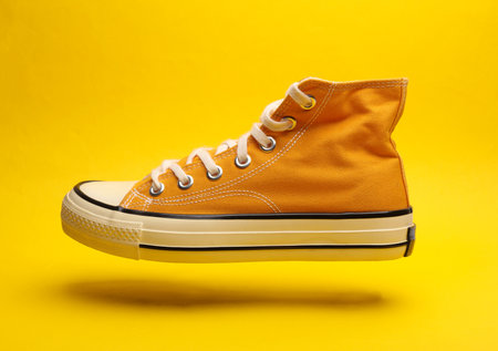 Old school rubber shoe floating on a yellow background