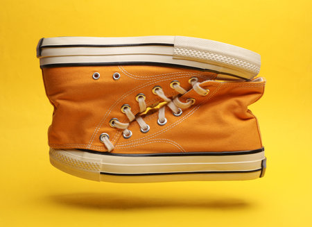 Old school rubber shoes floating on a yellow background