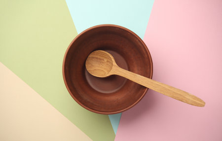 Clay bowl with wooden spoon on pastel background. Top viewの写真素材