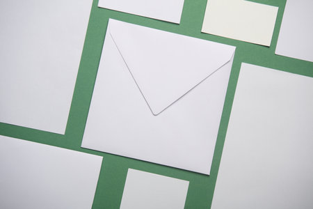 Mockup for design of white blank sheets of paper of different sizes and shapes, cards, envelope on green background. Corporate identification. Creative layoutの写真素材