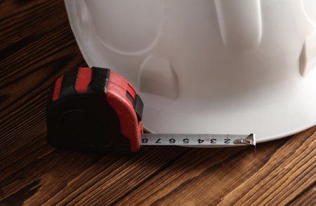 Construction helmet and tape measure on wooden boards