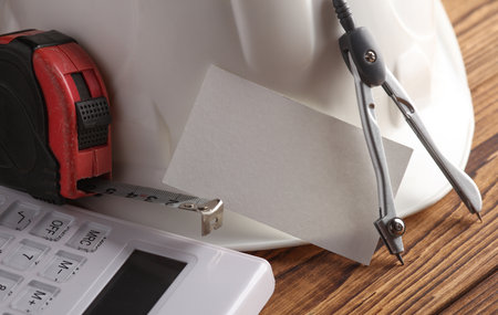 Engineer's tools and white blank business card on wooden boards.