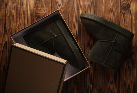 New Women's suede boots with fur in box on a wooden backgroundの写真素材