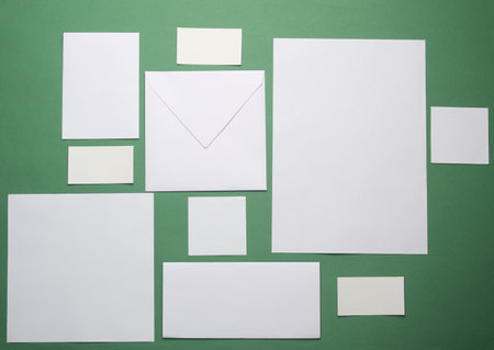 Mockup for design of white blank sheets of paper of different sizes and shapes, cards, envelope on green background. Corporate identification. Creative layoutの写真素材
