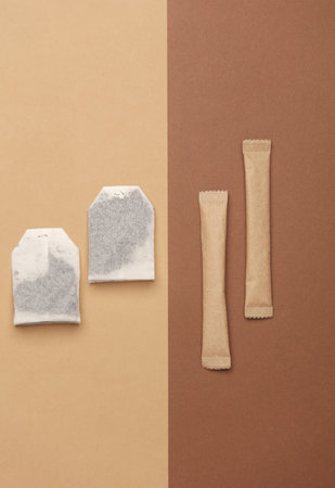 Tea bags and disposable sticks with sugar on a beige background. Top view. Flat layの写真素材