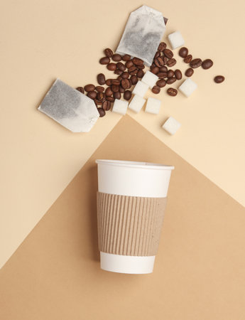 Sugar cubes, coffee beans and tea bag with cardboard cup for hot drinks on beige brown backgroundの写真素材