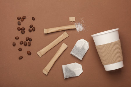 Cardboard cup, Coffee beans, tea bags and disposable sticks with sugar on a beige background. Flat layの写真素材
