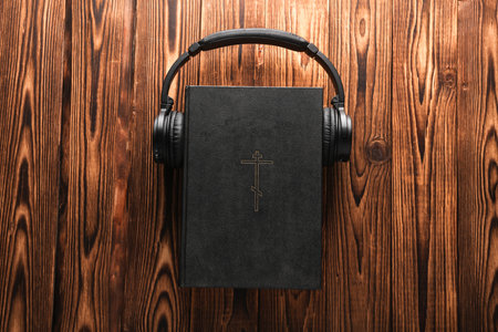 Bible with headphones on wooden table. Religious audiobookの写真素材