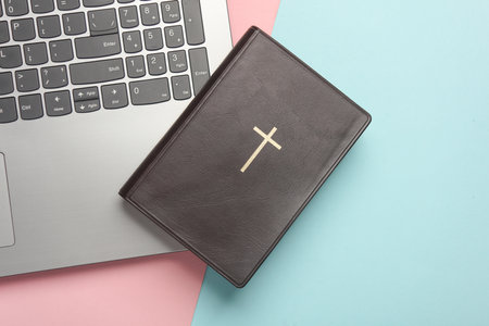 Bible book with laptop on pink blue background. Online Bible study. Flat lay
