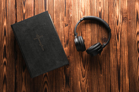 Holy Bible and headphones on wooden background. Top view with copy spaceの写真素材