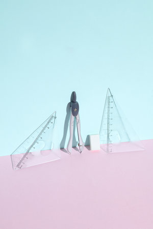Compasses with rulers and eraser on a pastel backgroundの写真素材