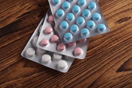 Blisters of tablets on a wooden table close-up