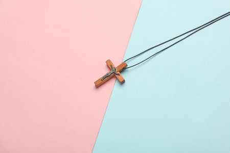 Wooden Christian cross on a string, pink blue backgroundの写真素材