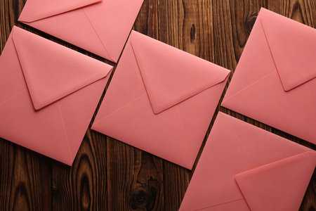 Pink square paper envelopes on wooden background