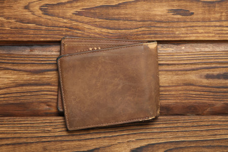 Old shabby leather wallet on a wooden table