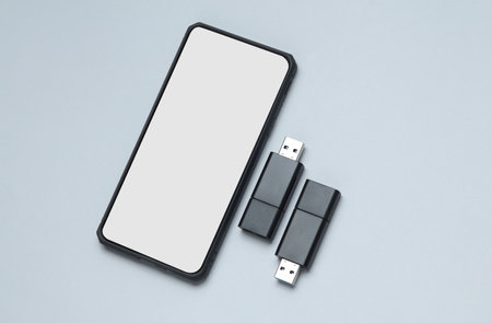 Smartphone and Two black USB flash drives on a gray background