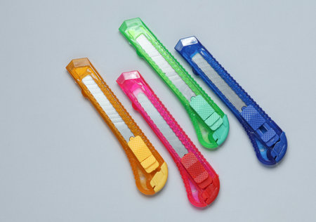 Plastic colored stationery knives for cutting paper on a gray backgroundの写真素材