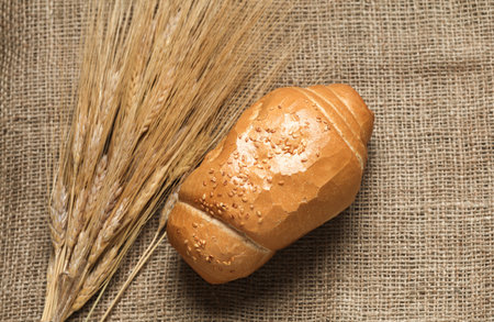 Spikelets of wheat and bun on burlap. Top view