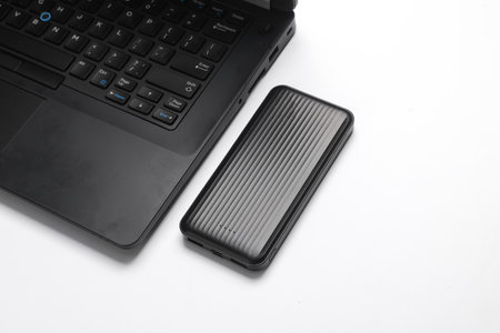 Laptop with power bank on white background
