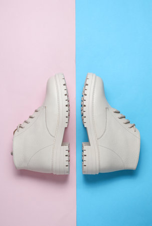 Women's white leather winter boots on a blue-pink background. Top viewの写真素材