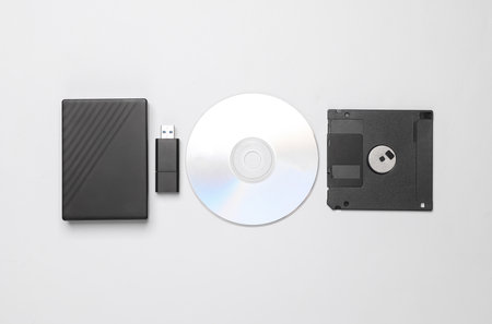 CD disk with floppy disk, USB flash drive and external hard drive on a white background. Digital...