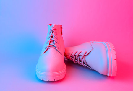 White leather boots in blue-red gradient neon light. Creative fashion still lifeの写真素材