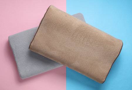 Orthopedic two pillows on a blue-pink pastel background. Healthy and comfortable sleepの写真素材