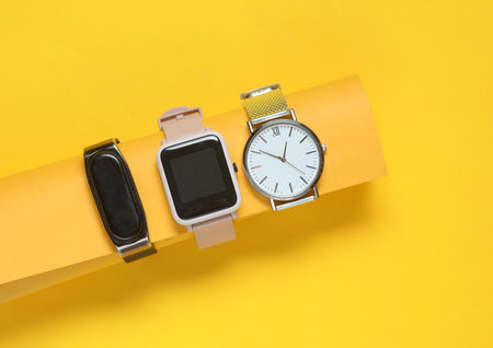 Modern smart and analog watches and bracelet on a yellow background.の写真素材