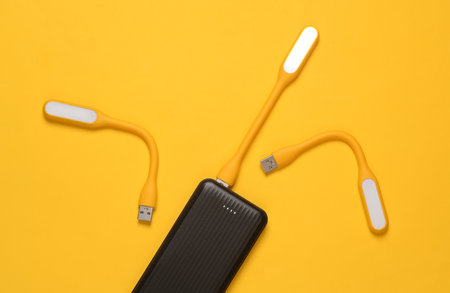 Power bank with Flexible yellow USB lamps on yellow background. Top view