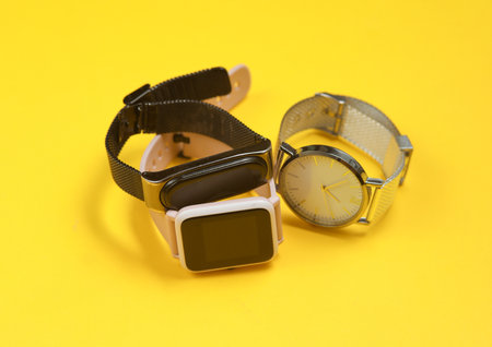 Modern smart and analog watches and bracelet on a yellow background.の写真素材
