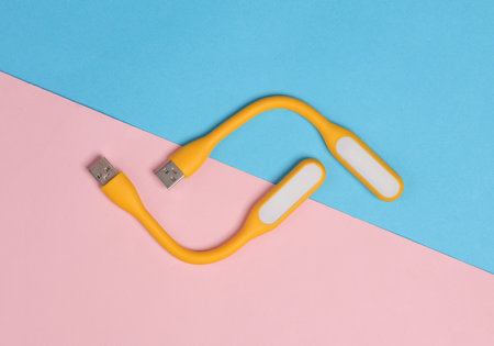Flexible yellow USB lamps on blue-pink background. Top viewの写真素材